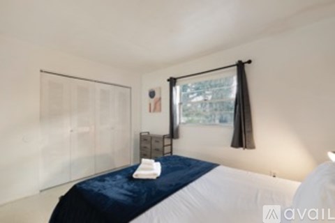 A bedroom with a bed, nightstand, and window.