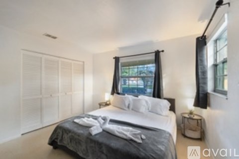 A bedroom with a large bed and a window with curtains.