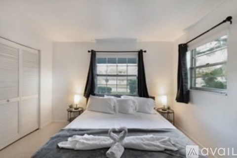 A bedroom with a large bed and two lamps on either side of the bed.
