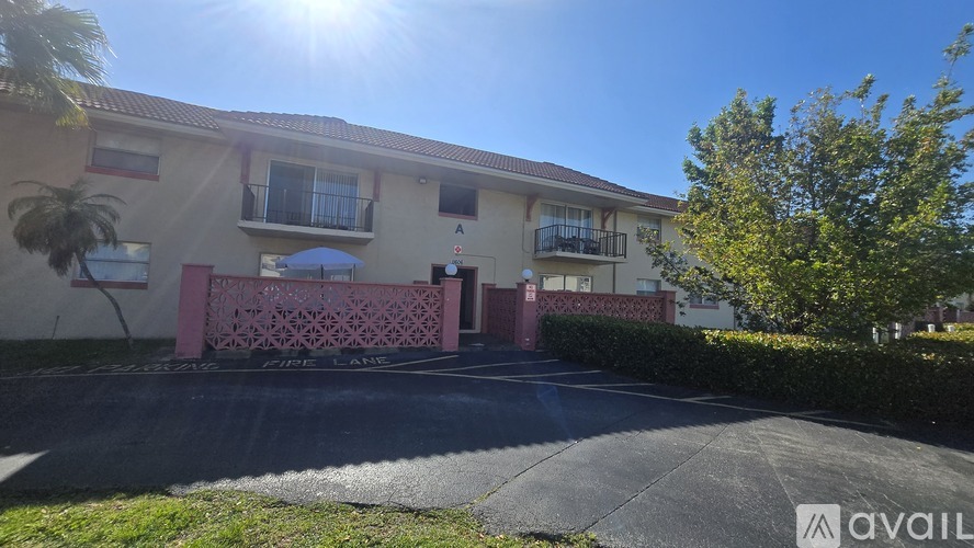 A sunny day at the apartment complex with a pink gate and palm trees.