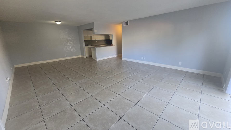 A spacious room with a tiled floor and a staircase in the background.