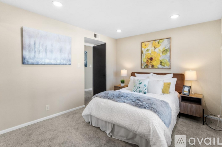 A bedroom with a bed, nightstand, and a painting on the wall.