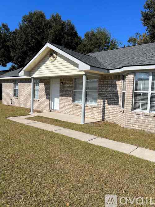 A house with a white door and windows is surrounded by a grassy area.
