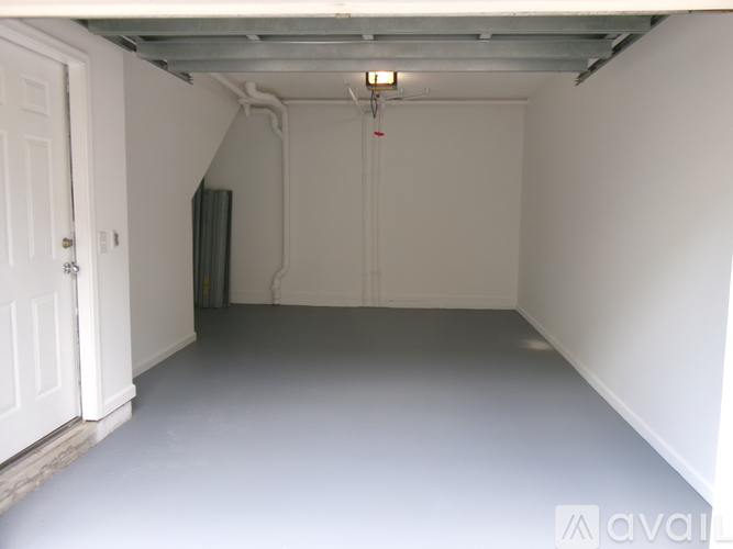 A spacious empty room with white walls and a white door on the left.