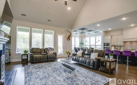 A spacious living room with a large grey sofa and a grey rug.