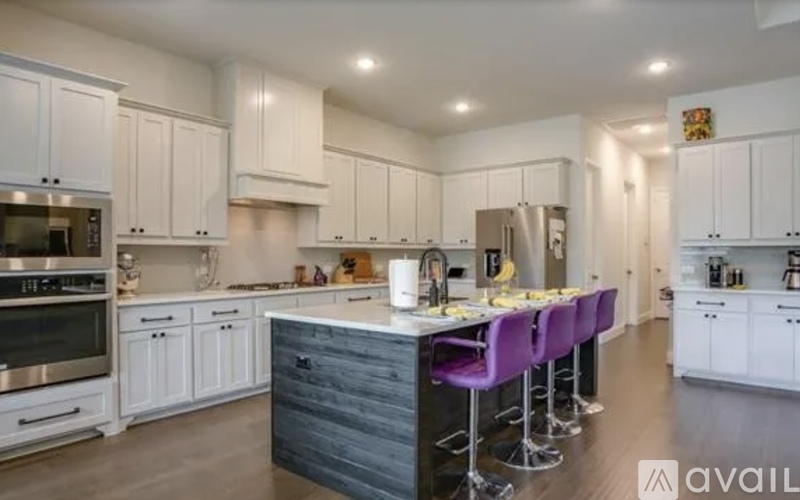 A kitchen with white cabinets and a dark island.