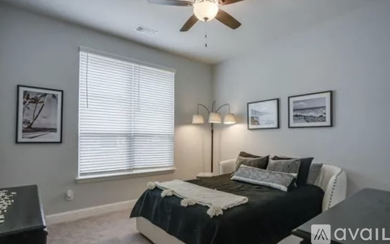 A bedroom with a bed, a ceiling fan, and pictures on the wall.
