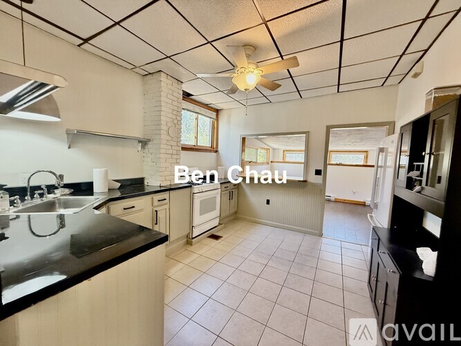 A kitchen with a black countertop and a fan on the ceiling.