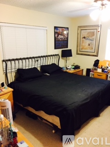 A bedroom with a black bedspread and a fan on the bed.