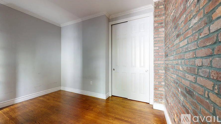A room with a white door and a brick wall.