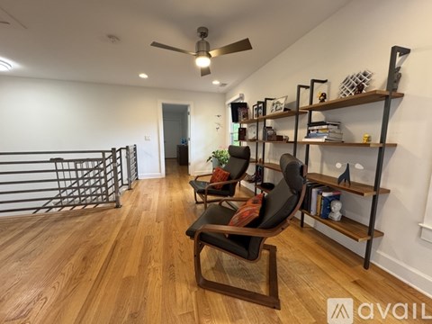 A living room with a black chair and wooden floors.