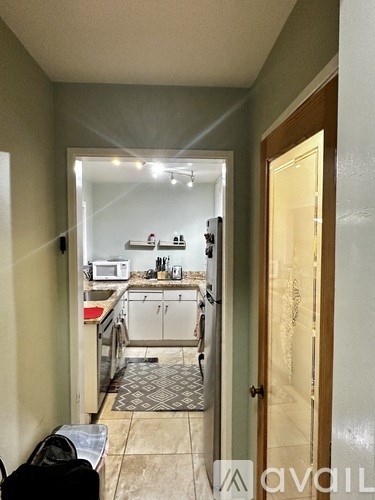 A kitchen with a microwave, oven, and sink is visible through an open door.