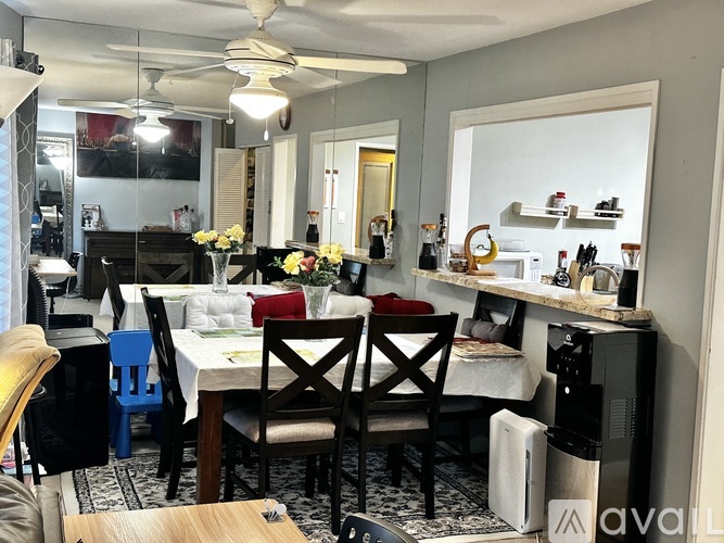 A dining area with a table set for four and chairs around it.