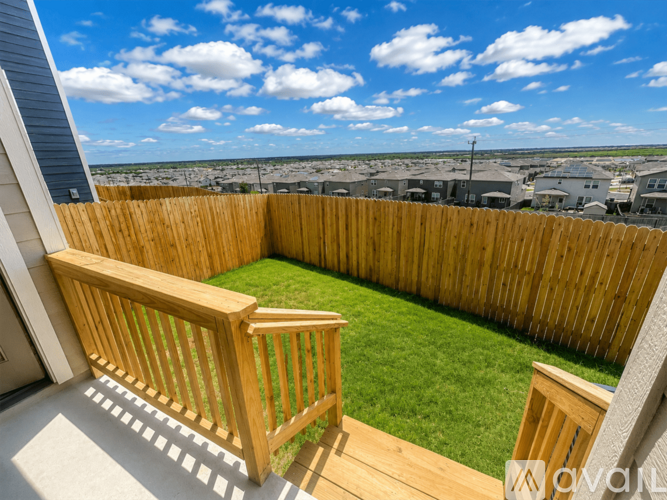 A wooden deck overlooks a grassy area and a row of houses.