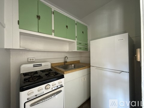 A kitchen with green cabinets and a white stove top oven.