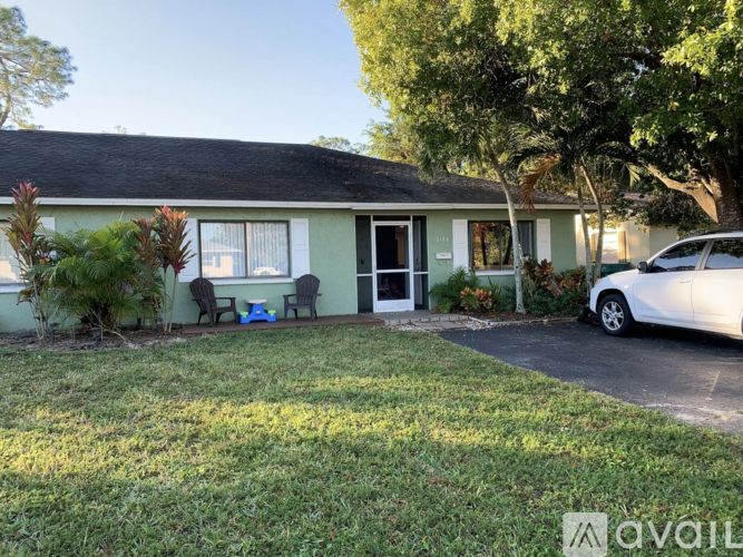 A house with a green exterior and a white car parked in front.