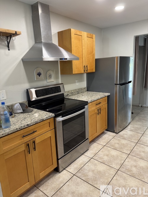 A kitchen with wooden cabinets and a stainless steel refrigerator.