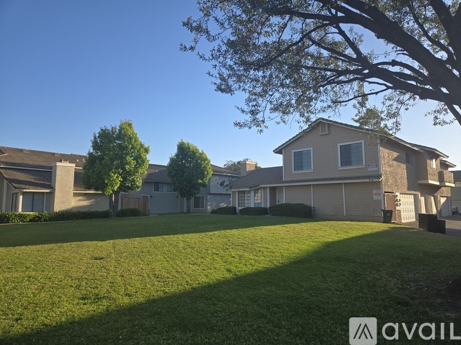 A house with a lawn in front and a tree to the left.
