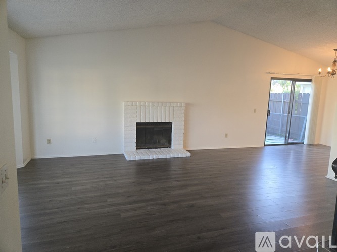 A large, empty room with a fireplace and wooden floors.