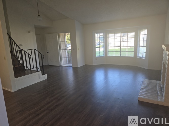 A spacious room with wooden floors and a staircase.