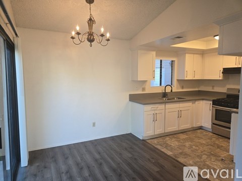 A kitchen with white cabinets and a wooden floor.