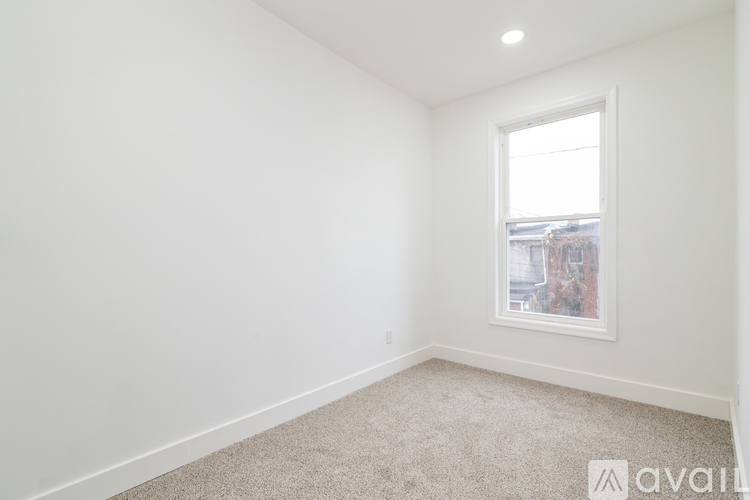 A room with a window and a carpeted floor.
