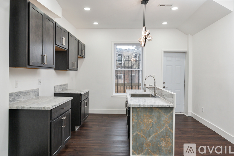 A kitchen with black cabinets and a marble countertop.