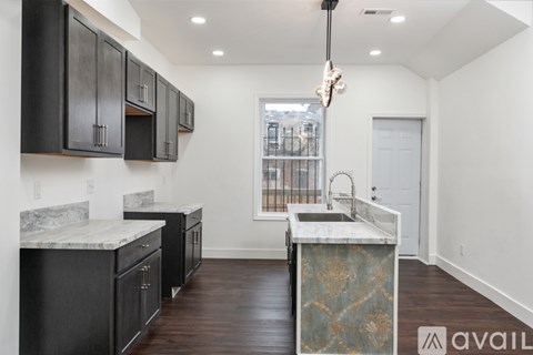 A kitchen with black cabinets and a marble countertop.