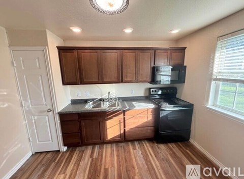 A kitchen with wooden cabinets and a black dishwasher.