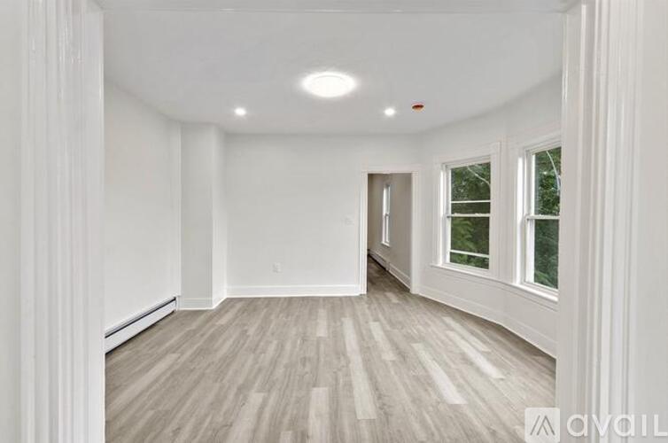 A spacious room with wooden flooring and white walls.