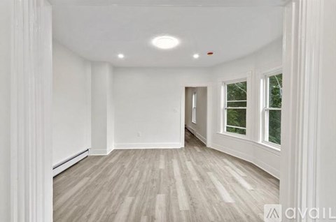 A spacious room with wooden flooring and white walls.