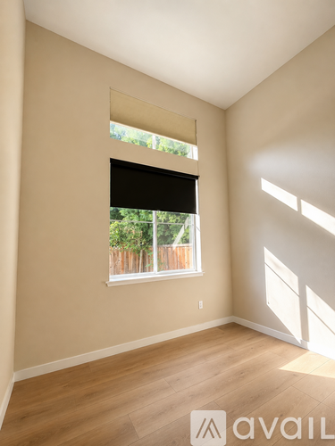 A room with a window and wooden flooring.