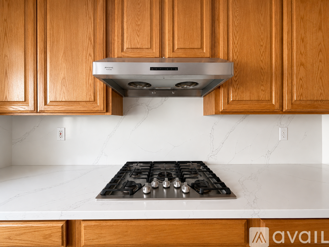 A kitchen with wooden cabinets and a stainless steel stove top.