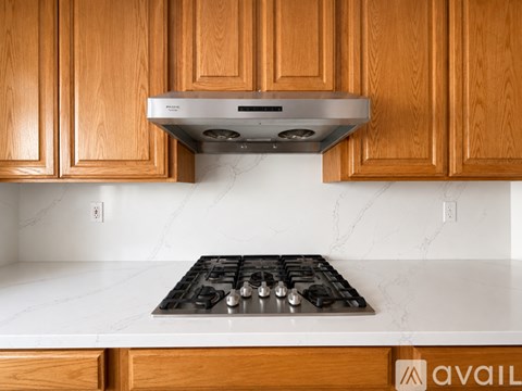 A kitchen with wooden cabinets and a stainless steel stove top.