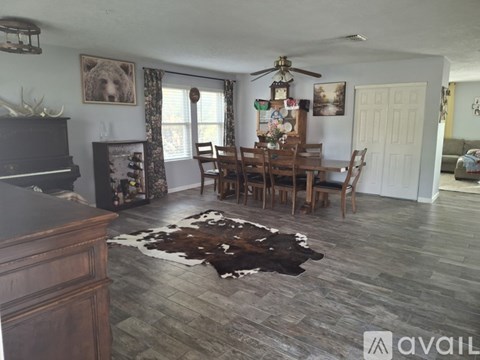A living room with a bear picture on the wall and a cowhide rug on the floor.