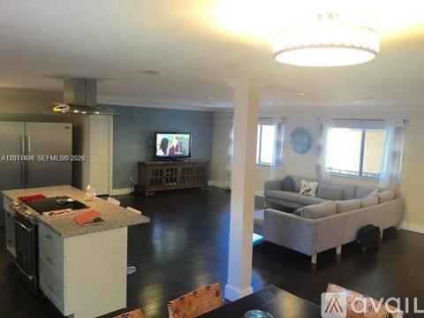 A modern kitchen with a large island and a living room with a couch and a TV.