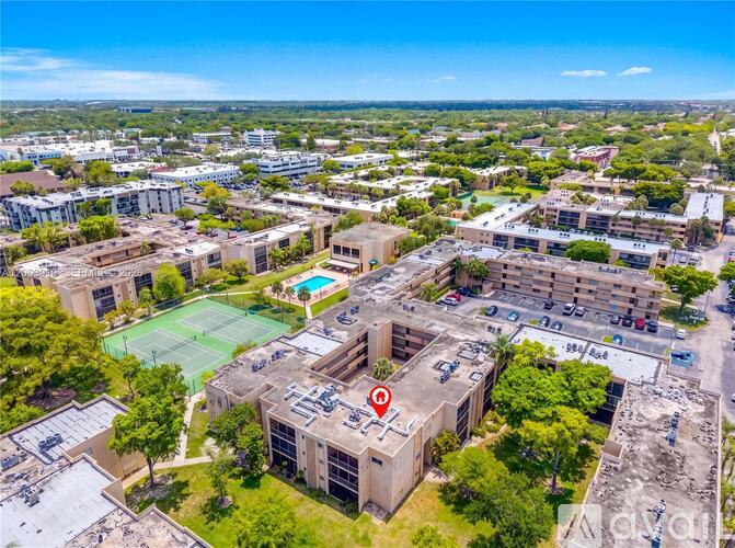 A bird's eye view of a tennis court surrounded by buildings.