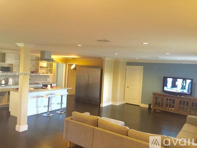 A living room with a couch, a television, and a bar area.