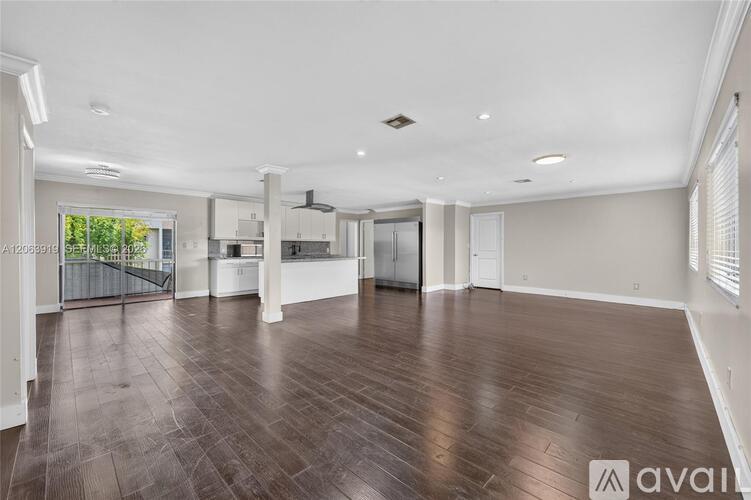 A spacious room with wooden flooring and white walls.