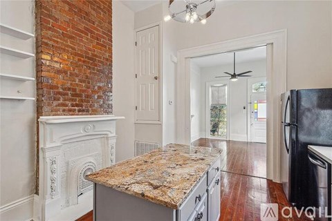 A kitchen with a granite countertop and a brick wall.