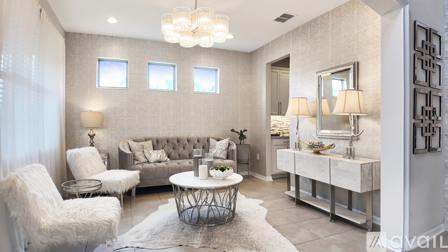 A modern living room with a grey sofa, a white chair, and a glass coffee table.