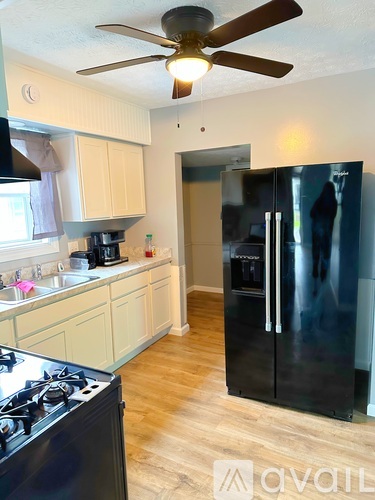 A kitchen with a black fridge and a black stove top.