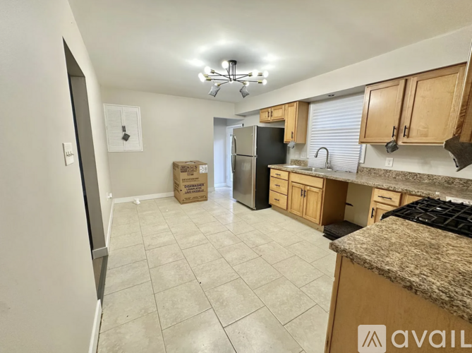 A kitchen with a refrigerator, cabinets, and a countertop is available for rent.