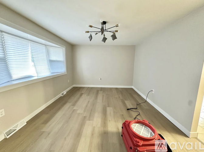 A room with a red vacuum cleaner on the floor.
