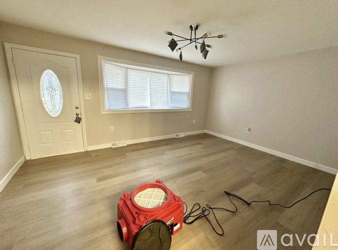 A room with a red vacuum cleaner on the floor.