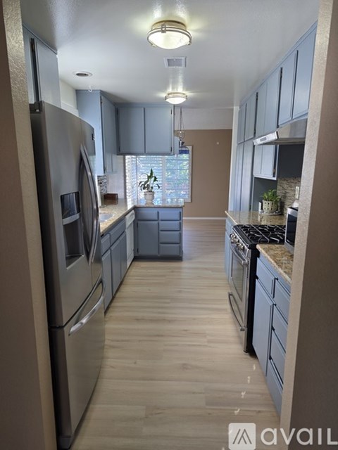 A kitchen with a refrigerator on the left and a stove on the right.