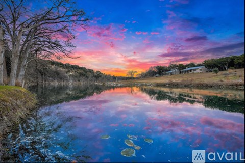 A serene landscape with a river reflecting the sky at sunset.