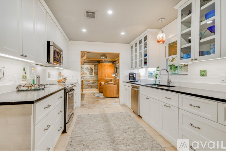 A kitchen with white cabinets and black countertops.