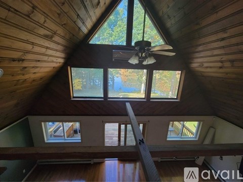 A view from the top of a wooden building looking down at a window and a fan.