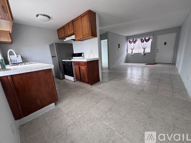 A kitchen with wooden cabinets and a black refrigerator.
